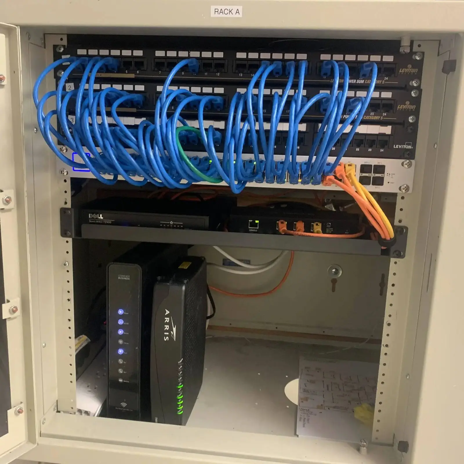 Wall cabinet with blue patch cables, patch panel and network equipment
