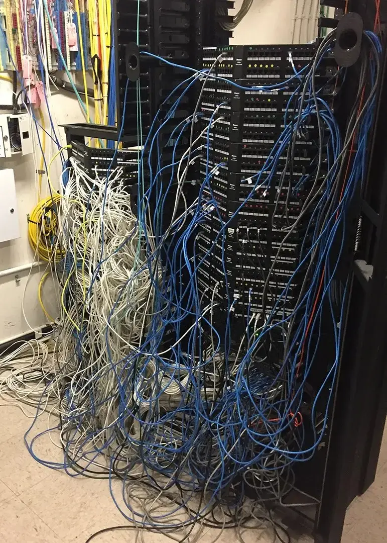 Network closet with tangled, unmanaged cabling before a structured cabling install